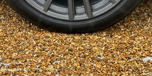 Driveway golden gravel secured with a heavy-duty gravel grid which is holding the weight of a car
