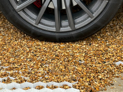 Driveway golden gravel secured with a heavy-duty gravel grid which is holding the weight of a car