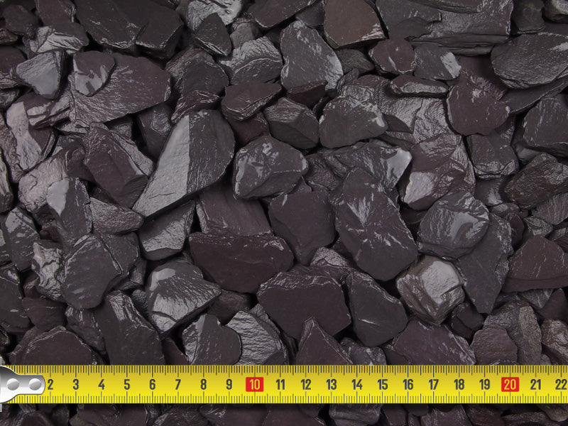 Wet blue slate chippings with a measuring tape demonstrating that the chips are sized between 10-20mm