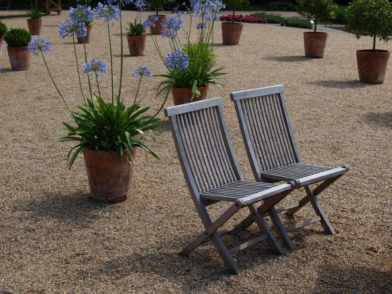 Two lawn chairs on an aggregate surface