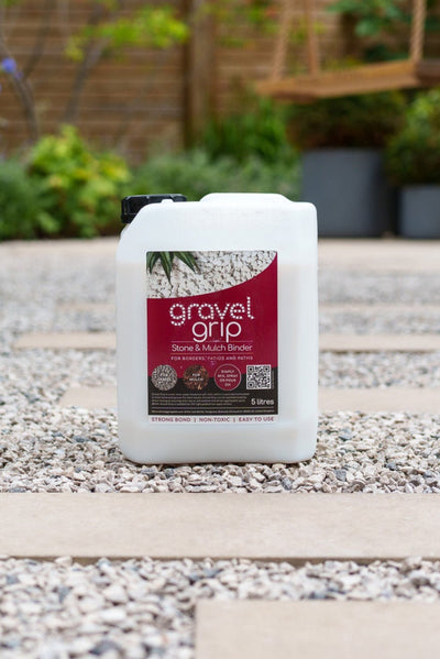 Container of Gravel Grip on a gravel surface with plants in the background