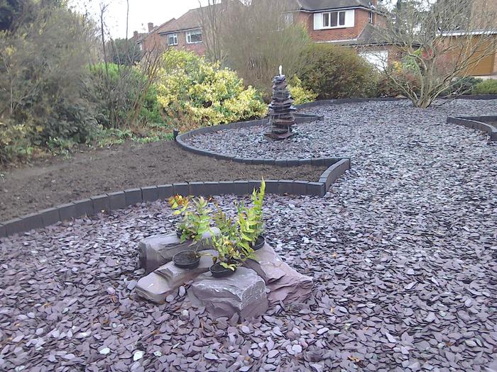Close of plum slate arranged in circles with plants and rockery