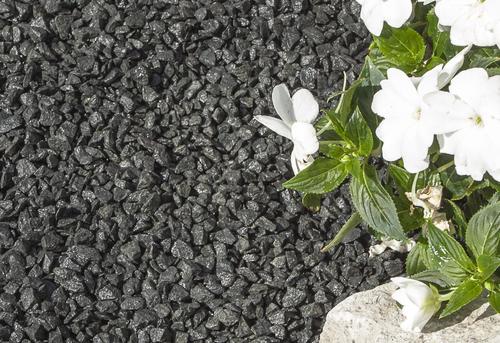 black gravel for garden laid next to white flowers 