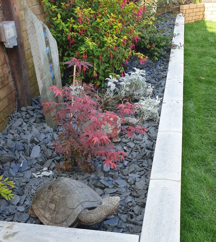 Grey Slate Chippings Next To Plants In Garden