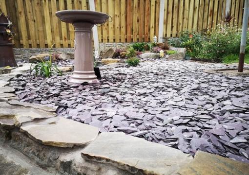 plum slate chippings used as a ground cover around a water feature and other garden areas