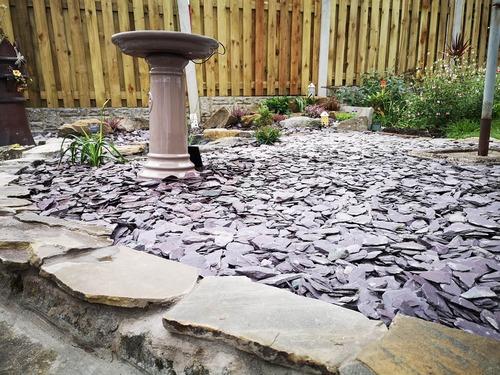 plum slate chipping ground cover surrounding a water feature, plants and grass