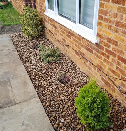 pea pebbles laid around shrubs and plants of front garden