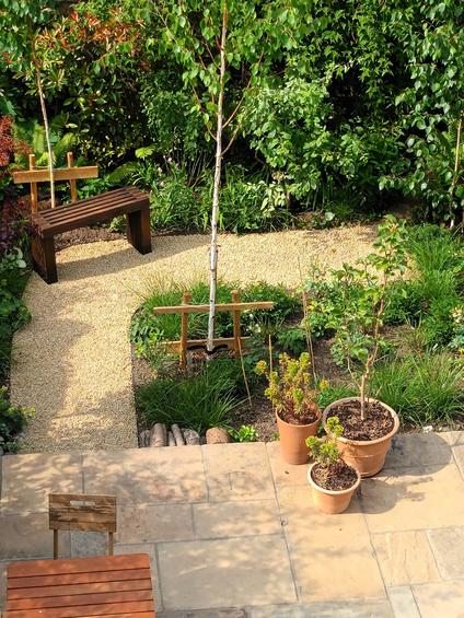 natural gravel pathway laid in back garden surrounded by green plants and small bench